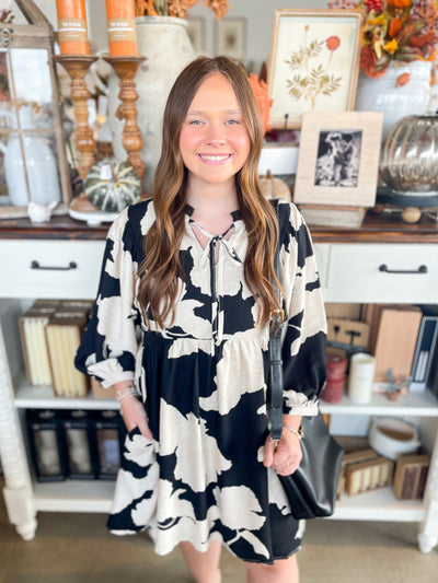 black, white, and tan floral long-sleeve short dress with tie neck detail 