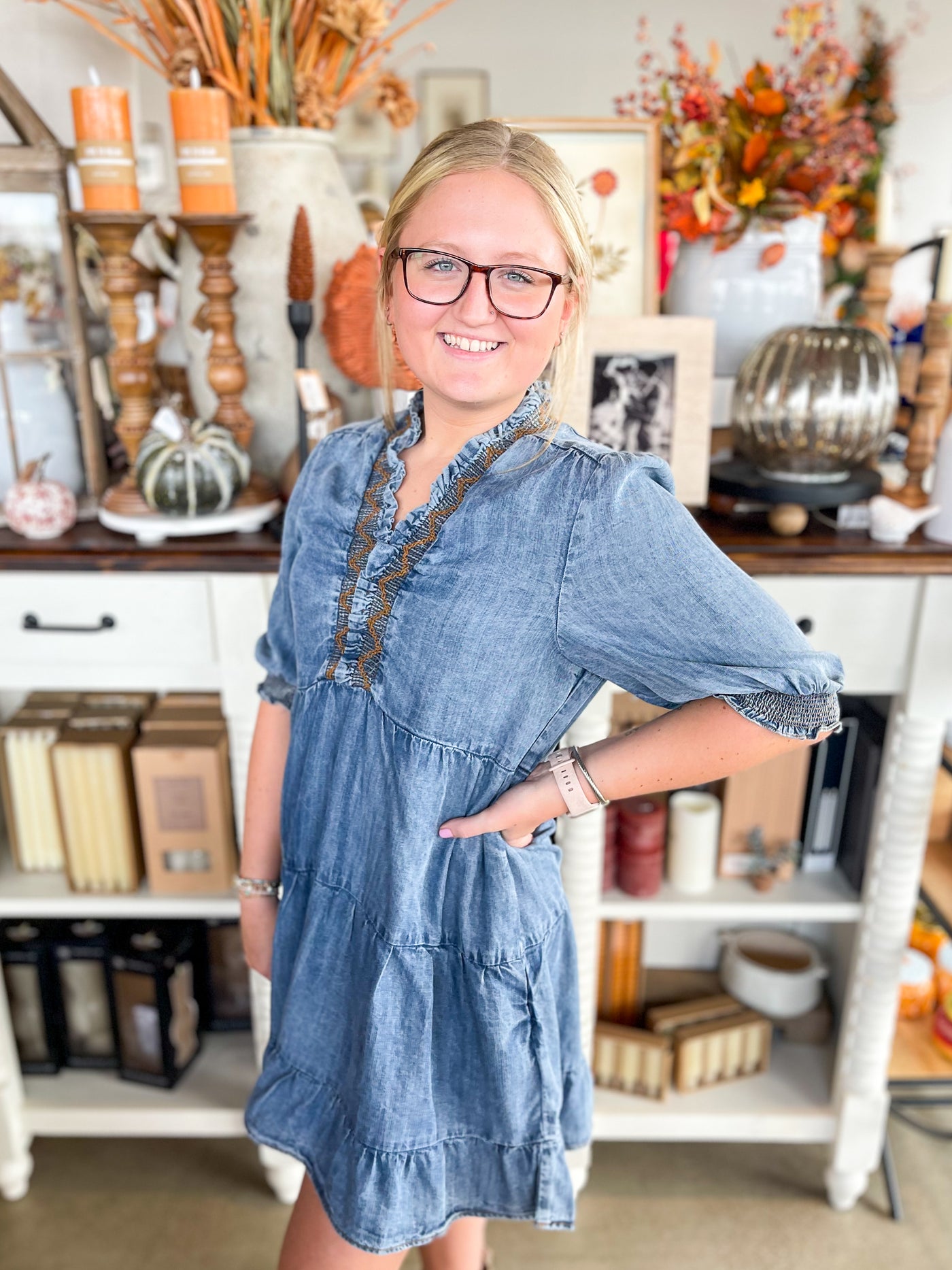 denim dress with brown stitching and smocking at the neckline and ruffle hem at the bottom 